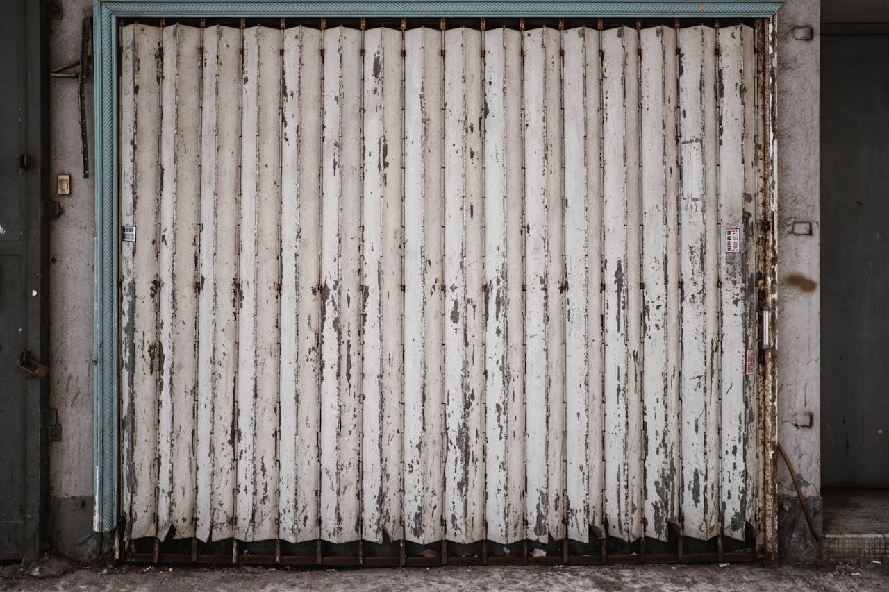 A textured, rusty metal garage door in an urban street setting, Hong Kong.